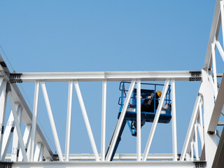 Naklejka premium construction worker at construction site using lifting boom machinery