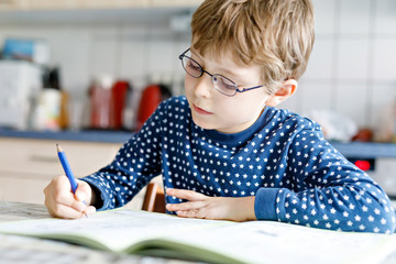 preschool kid boy at home making homework writing letters with colorful pens