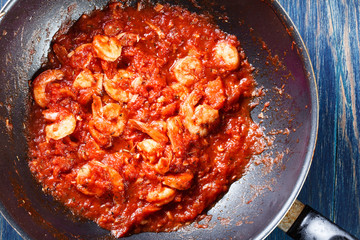 Shrimp with tomato sauce and herbs on a pan