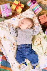 Baby and presents. Child on a pillow. Celebrate the first Christmas.