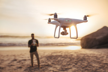 Young man on the beach flying a drone
