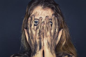 Scared young woman with dirty face and arms