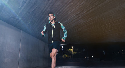 Young man jogging at night in city