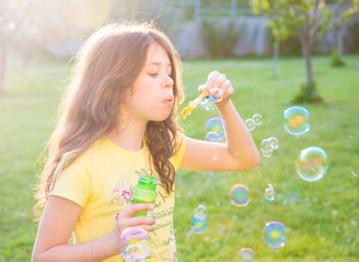 Girl blowing soap bubbles outdoors