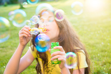 Girl blowing soap bubbles outdoors