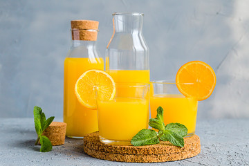 Fresh Orange Juice in Glass and Bottles and some Ripe Oranges on Grey Background. Healthy Drink, diet or Detox. © shutnica