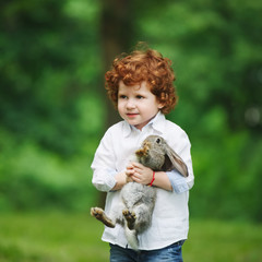 little boy with rabbit on grass