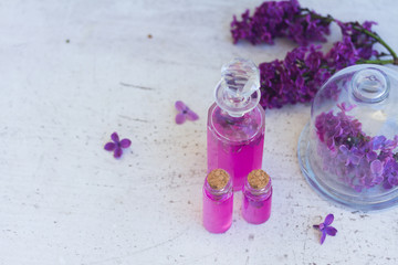 Obraz na płótnie Canvas Lilac essence in glass vials on wooden white table