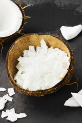 Half of ripe coconut and coconut shavings on a dark background