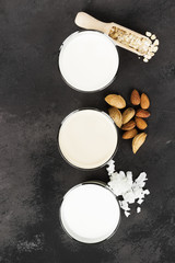 Obraz na płótnie Canvas Vegan oat, almond, coconut milk in glass on a dark background. Non-dairy milk. Top view. Food background