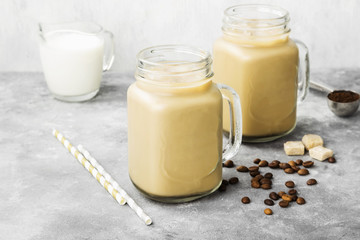 Ice coffee with milk in a tall glass on a gray background