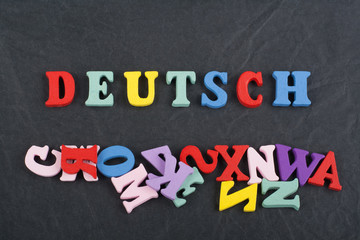 DEUTSCH word on black board background composed from colorful abc alphabet block wooden letters, copy space for ad text. Learning english concept.