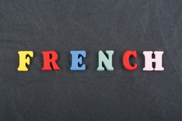 FRENCH word on black board background composed from colorful abc alphabet block wooden letters, copy space for ad text. Learning english concept.