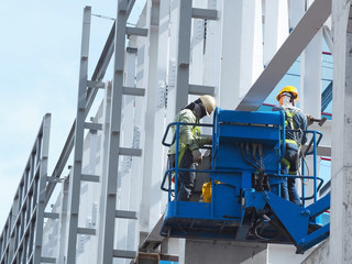 construction worker at construction site using lifting boom machinery