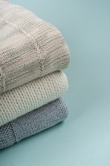 Knitted wool sweaters. Pile of knitted winter clothes on wooden background, sweaters, knitwear, space for text.