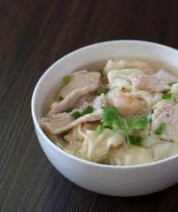 Shrimp wonton with braised pork in soup on wooden table / Select focus image