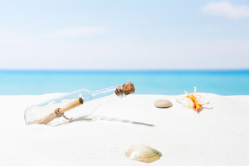 Message in bottle on beach with white sand,  in tropical sea