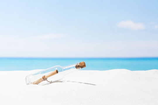Message in bottle on beach with white sand,  in tropical sea