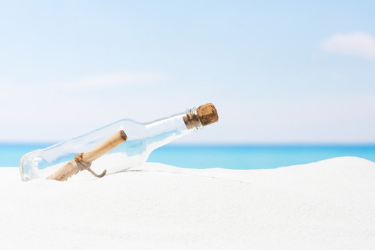 Message in bottle on beach with white sand,  in tropical sea