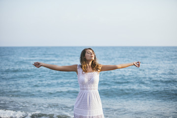 Fototapeta na wymiar Beautiful woman on the beach in a white dress happy