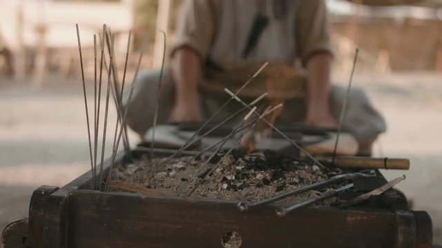 Medieval man inflates the fire in the field