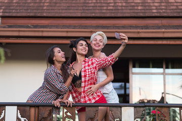 Naklejka premium Young Girls Group On Terrace Taking Selfie Photo On Cell Smart Phone, Beautiful Woman Friends Communication Outdoors