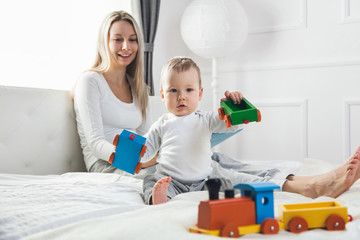 Happy mother with her cute child on the bed having a good time