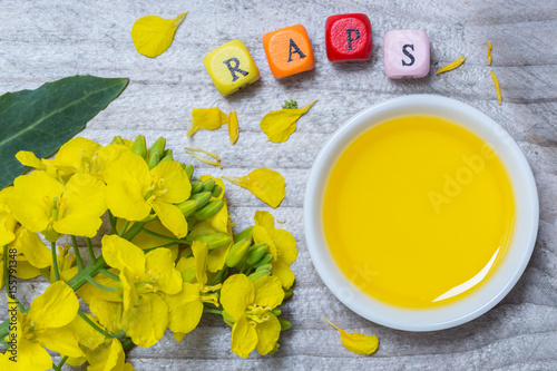 "Raps mit Blüten und Öl Konzept vor grauem Holz" Stockfotos und