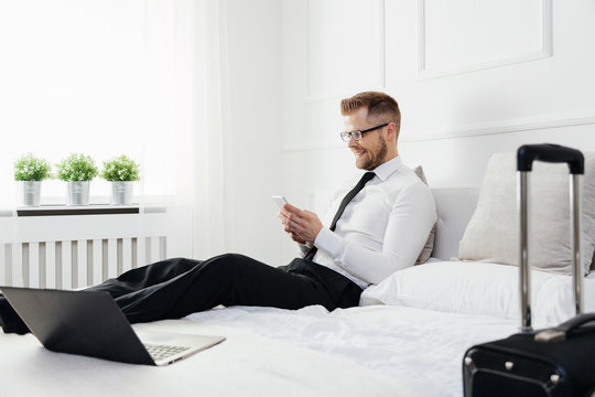 Businessman working from a hotel room with his mobile phone