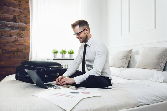 Businessman on bed working with a laptop from his hotel room