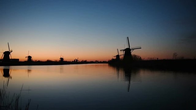 Traditional Dutch windmills from the channel Rotterdam at sunset. Water mirror effect. Holland.