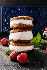 Homemade ice cream sandwiches  with  raspberries and mint on old black wooden over  texture background.