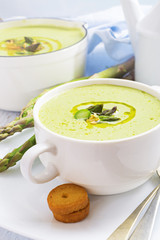 Asparagus cream soup with olive oil in white bowl
