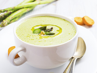 Asparagus cream soup with olive oil in white bowl
