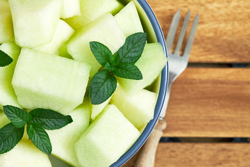 Sweet ripe muskmelon (galia melon) cut and served with mint leaves. Top view with copy space - obrazy, fototapety, plakaty