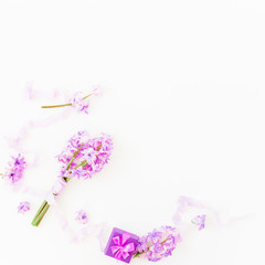 Bouquet of pink flowers, box and shabby tapes on white background. Flat lay, top view. Beauty background
