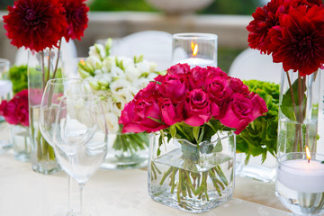 dining table decorated with white roses, red gerberas and candles awaits guests