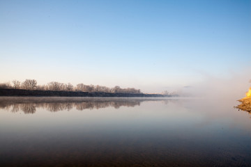 Fototapeta premium A misty dawn on the river in the early morning in the village