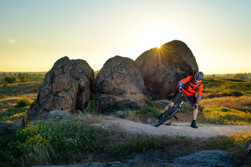 Cyclist Riding the Mountain Bike on Trail near the Beautiful Rocks at Sunset. Extreme Sport Concept.