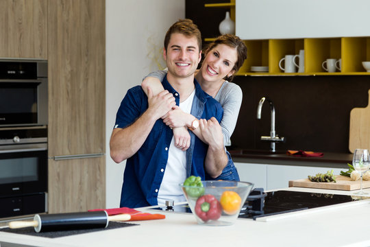 Beautiful young couple looking at camera in the kitchen at home.