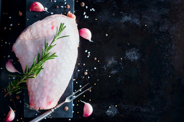 Fresh raw turkey thigh meat on a black background with spices and salt, top view, copy space