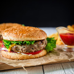 Classic american hamburger with beef and french fries on dark background