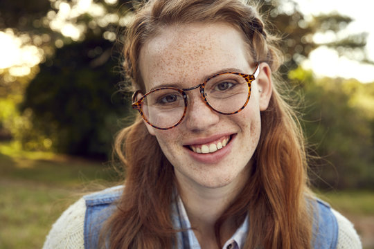 Portrait of redheaded young woman with freckles wearing glasses