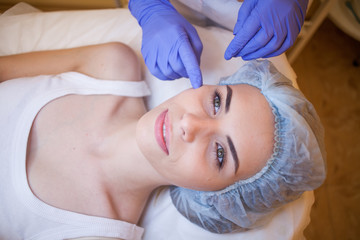 Obraz na płótnie Canvas doctor cosmetologist shows on face patient Spa