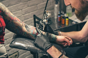 Serene bearded man creating tattoo on hand