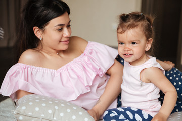 Amazing young mother lies on bed with her little daughter