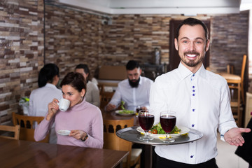 Fototapeta na wymiar Waiter welcoming guests in restaurant