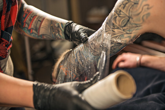 Naklejki Woman enveloping tattoo arm of client