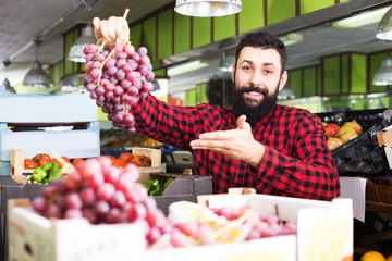 Shop assistant demonstrating grapes