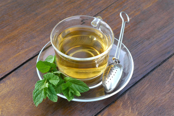 Glass cup of mint tea with mint leaves and tea holder spoon